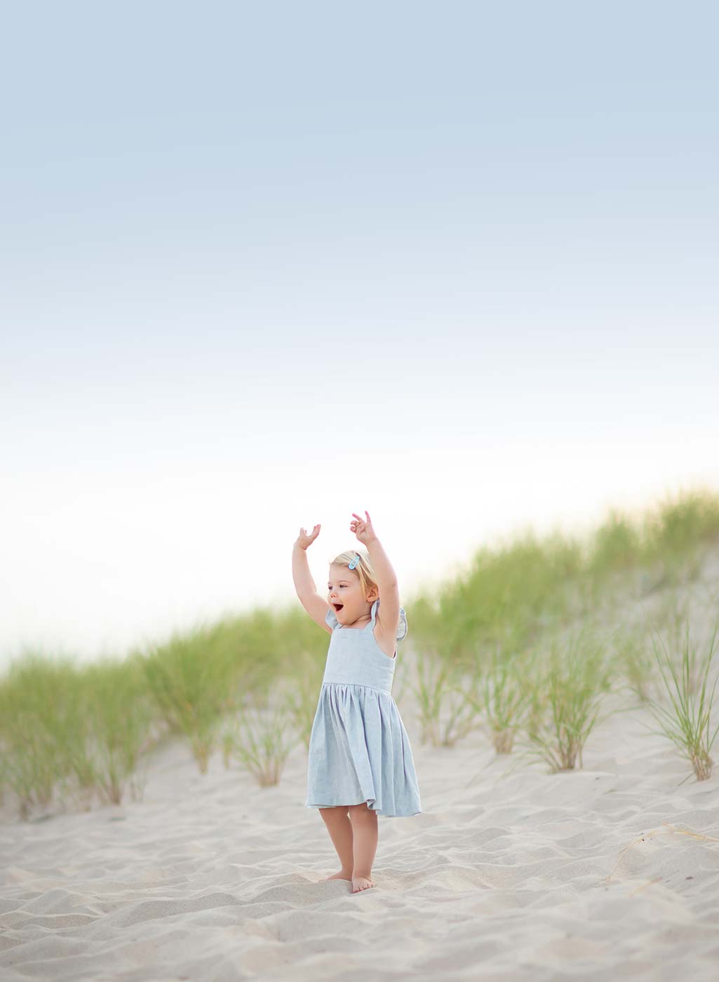Young girl in a dress waving her hands at a beach in East Hampton NY