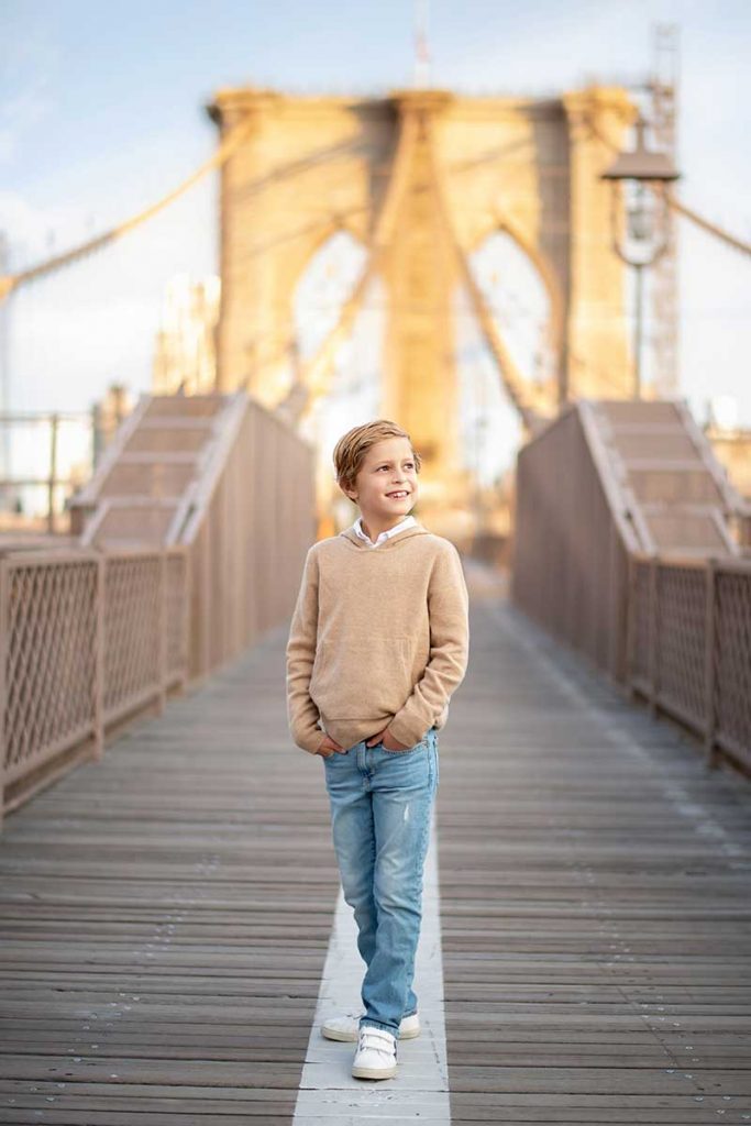 Stylish boy walking down Brooklyn Bridge in NYC