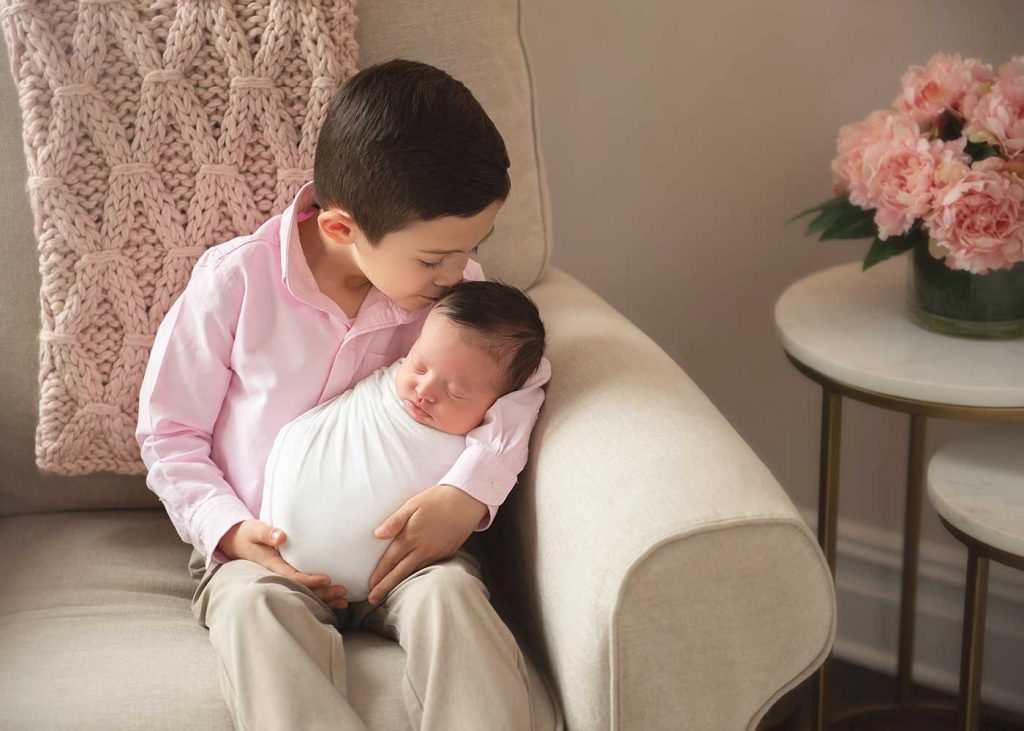 Boy holding his baby brother on a chair at their stylish NYC apartment