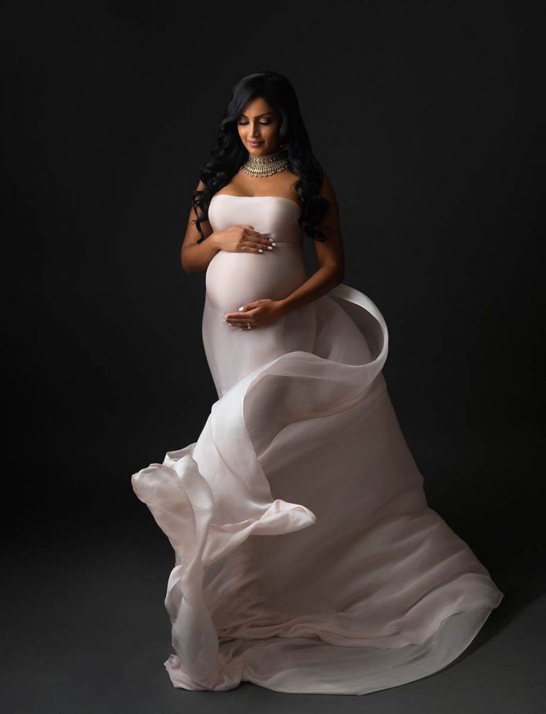 Flowing silk fabric envelops a woman in this stunning maternity photo