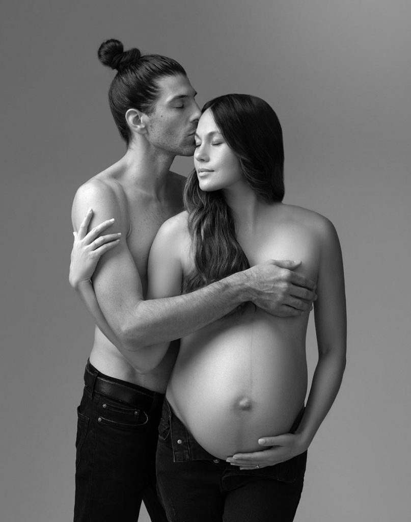 Black and white image of a husband hugging his pregnant wife