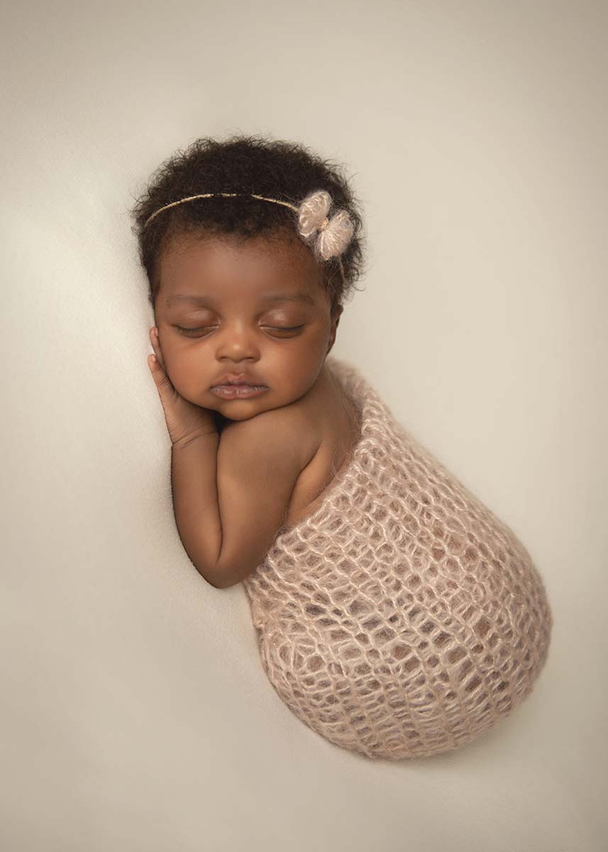 Baby with curly hair and headband posing for a newborn portrait