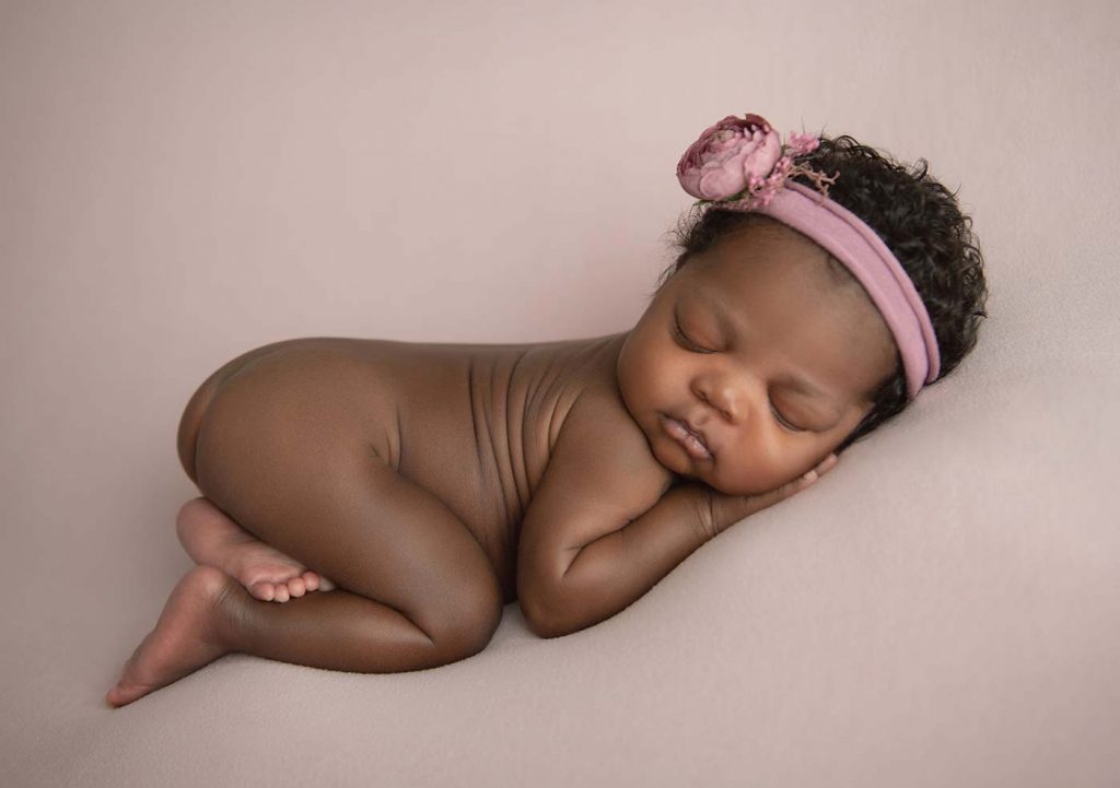Baby girl with a pink headband sleeping at a NYC photo studio