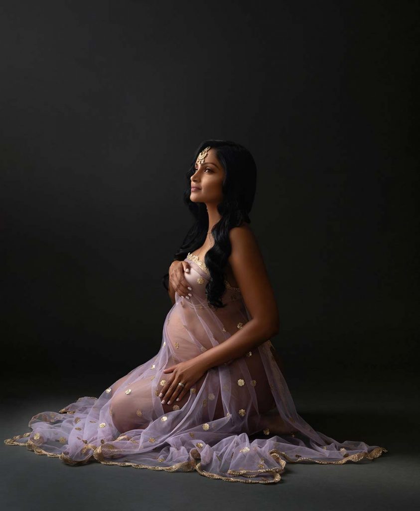 Purple fabric draped over a pregnant woman sitting on the studio floor