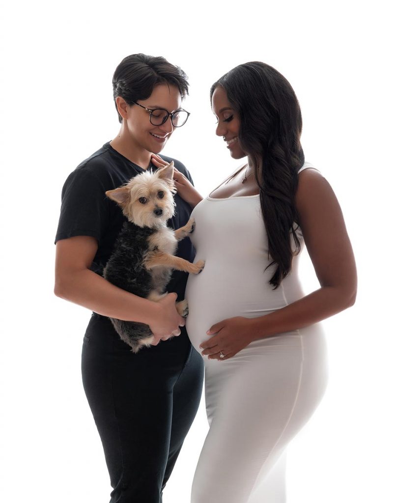 Couple posing for a pregnancy portrait along with their family pet