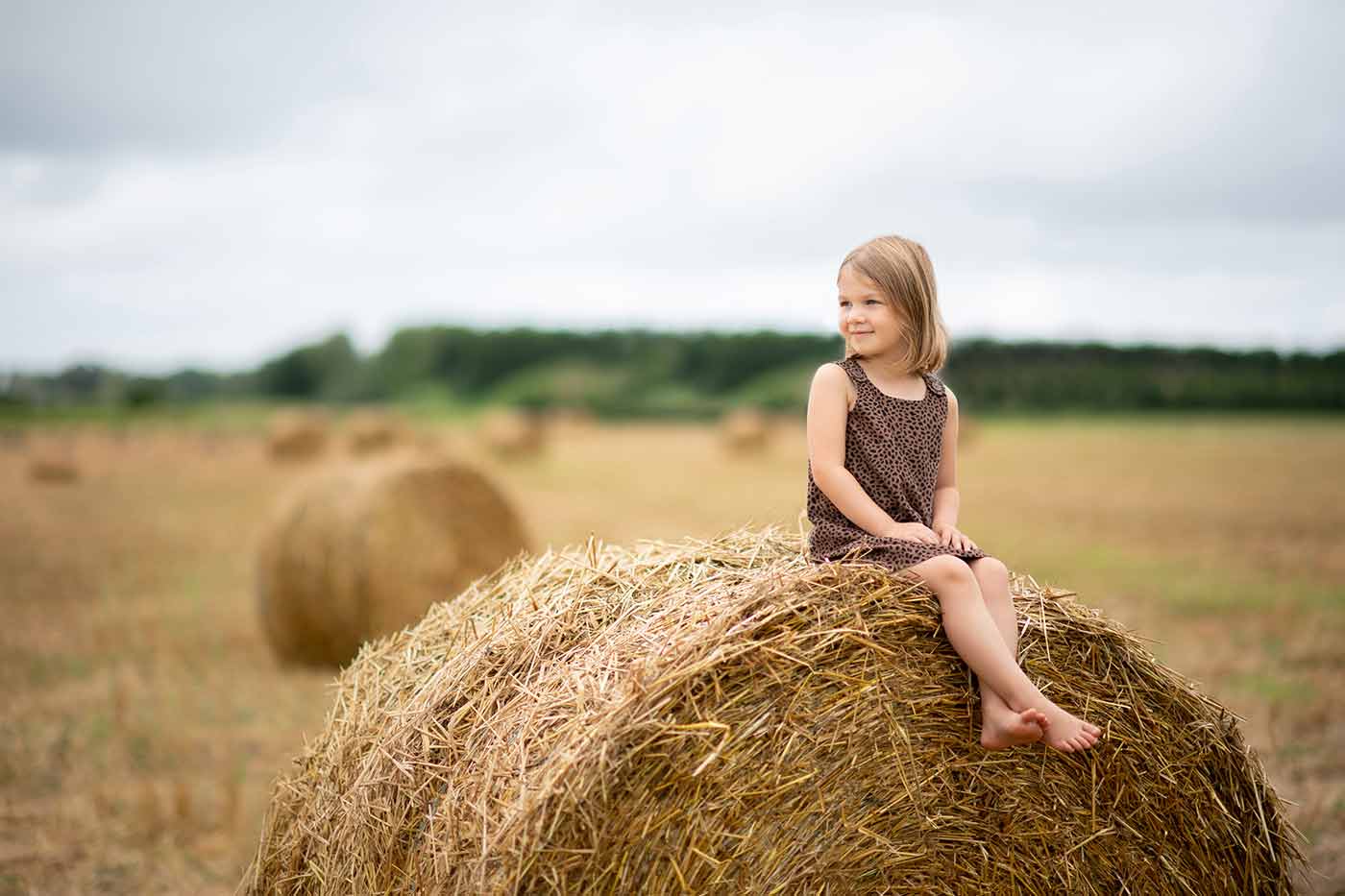 Girl in a dress sitting on rolled hay in Hamptons NY