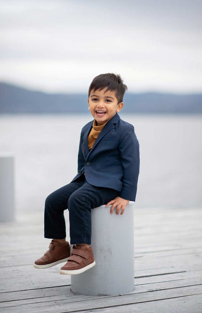 Toddler boy in a suit sitting on the shore of Hudson River NY