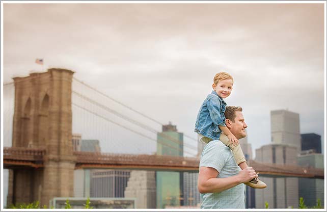 Little boy getting a piggy back ride on his Dad's shoulders near Brooklyn Bridge, NYC.