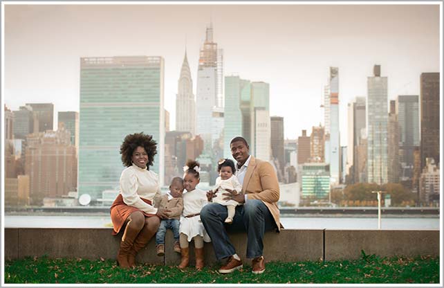 A stylish NYC family poses for a portrait with a picturesque backdrop.