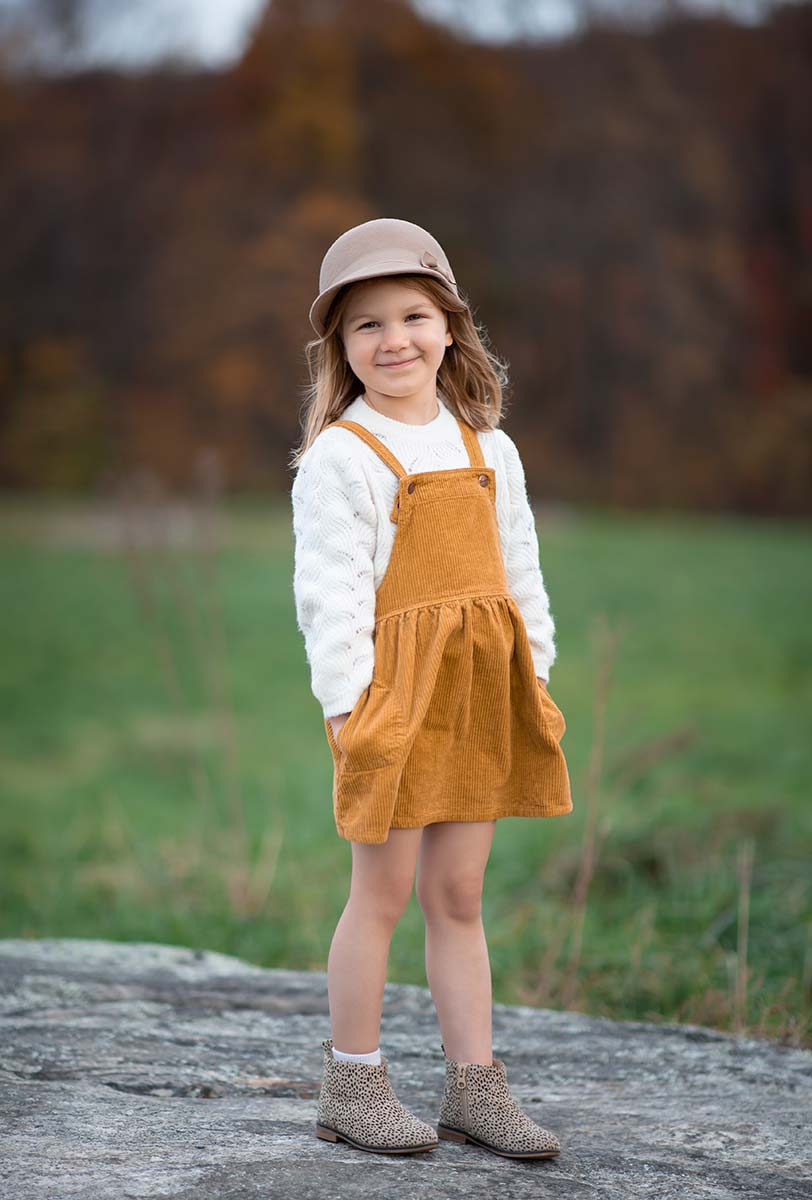 Girl wearing a cute mustard dress and a hat at a county park in Westchester NY