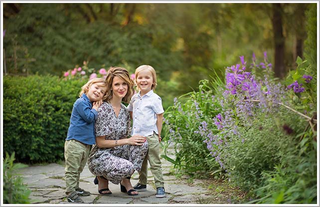 Overjoyed mother standing with her two baby boys surrounded by blooming flowers.