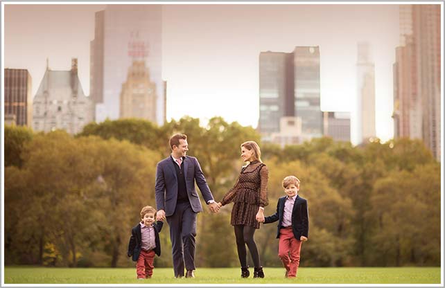 Parents holding hands with their children with the iconic NYC skyline.