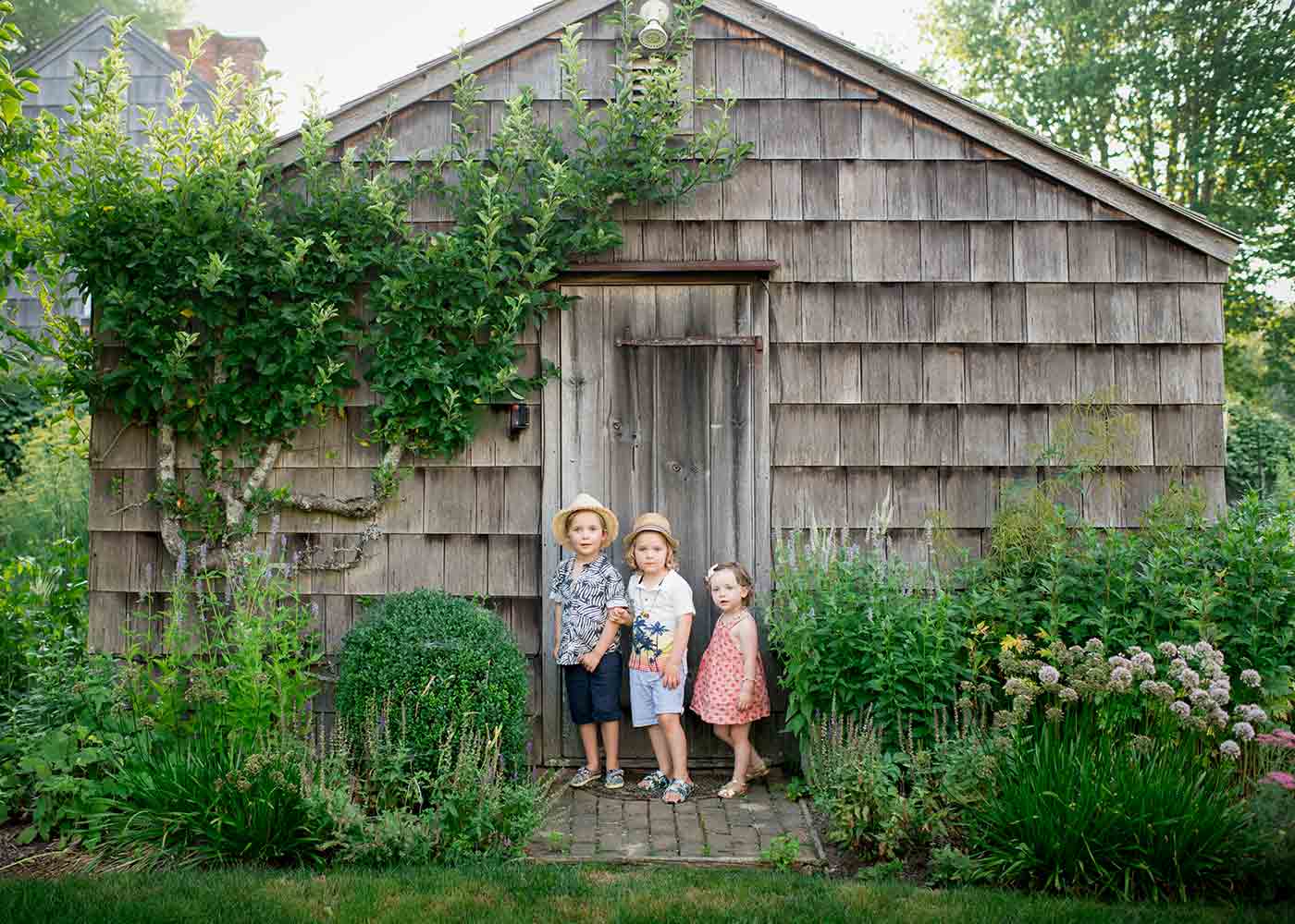 Siblings playing near a farmhouse in Easthampton, NY