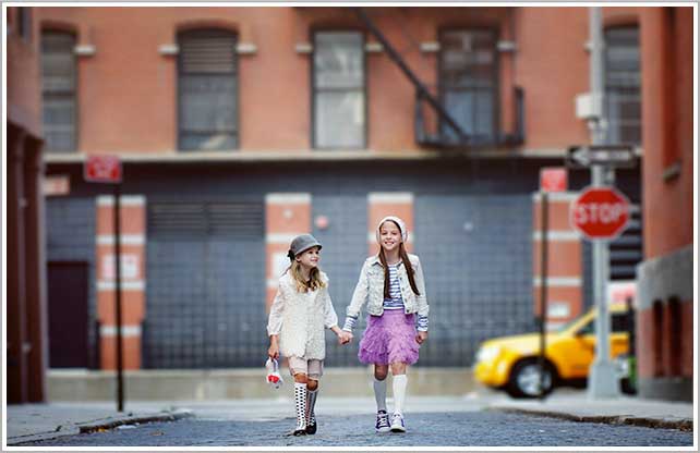Two sisters, dressed in stylish urban clothes walk down a street in Tribeca neighborhood of New York City.
