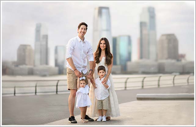 Beautiful family photo of a NYC family standing on the waterfront with their two children.