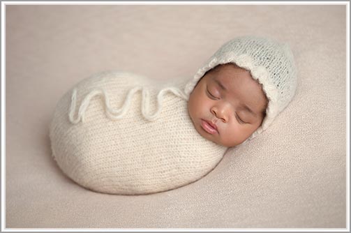 Classic newborn photo of a baby swaddled in a wrap, sleeping peacefully.