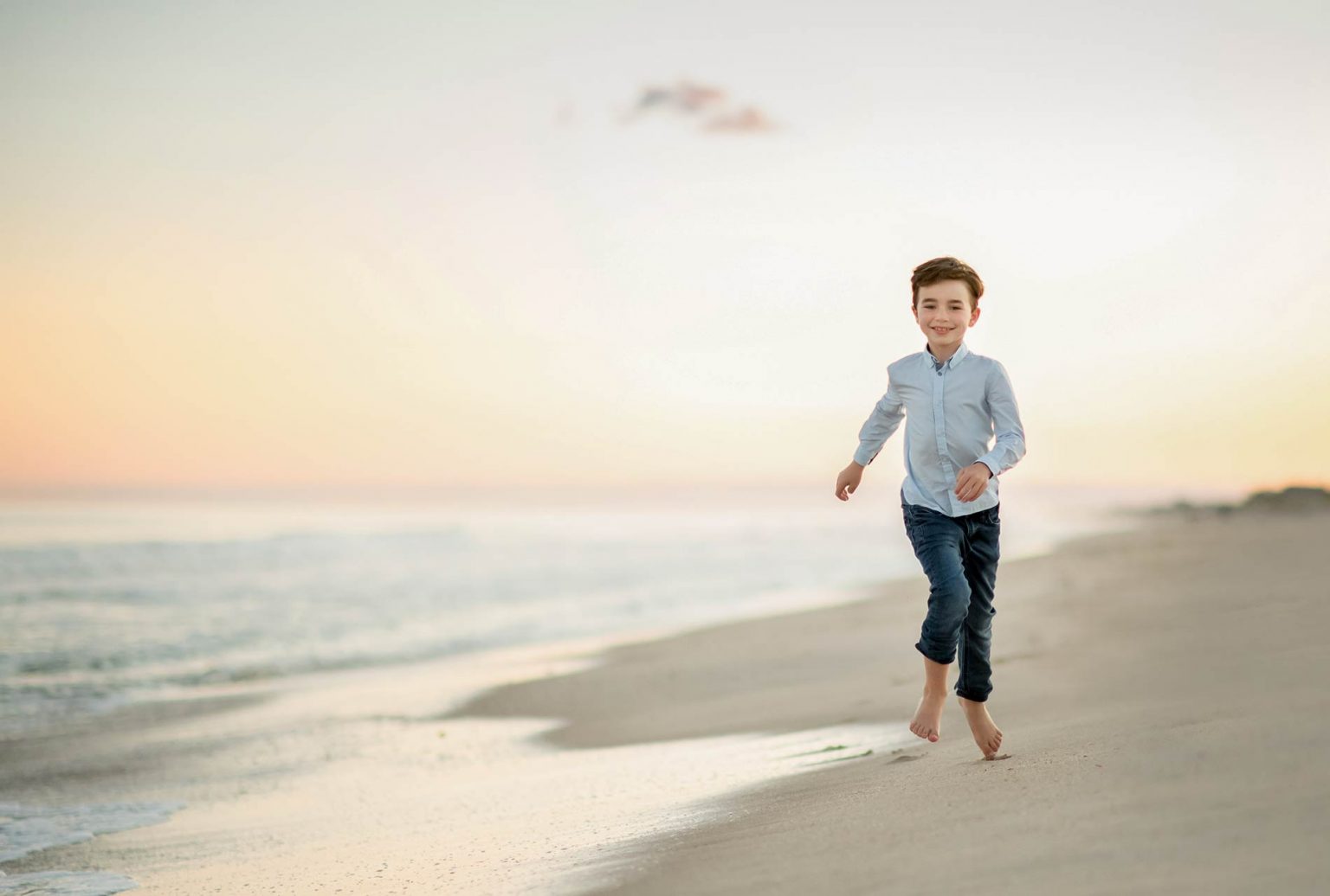 boy running in the sand at beach family photoshoot