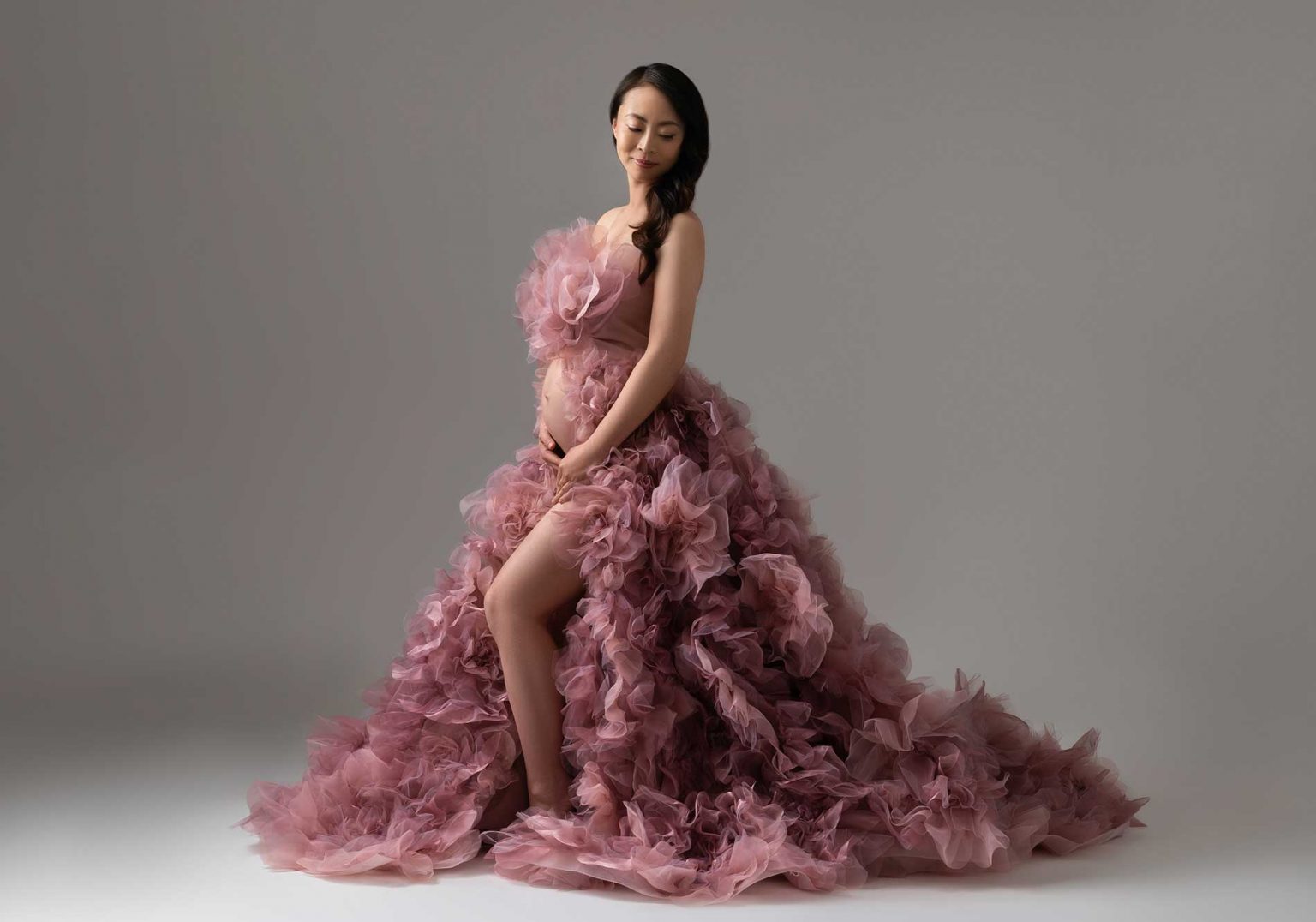 Elegant maternity photography wearing pink ruffle floral gown