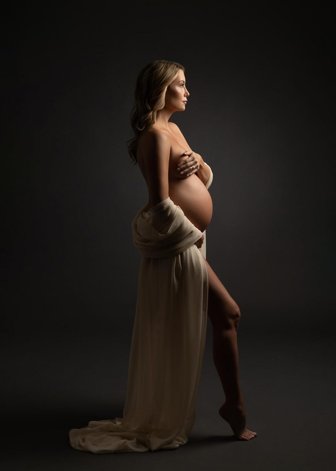 Intimate portrait of pregnant woman with draped silk