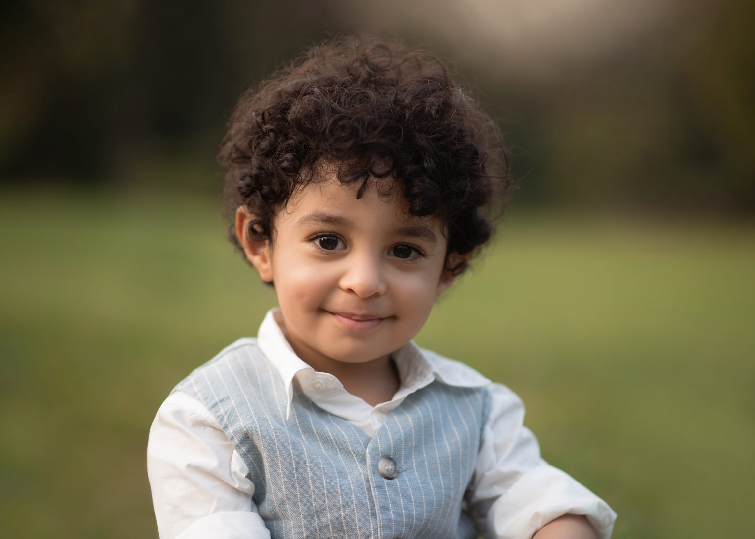 little boy with curly hair sitting in central park