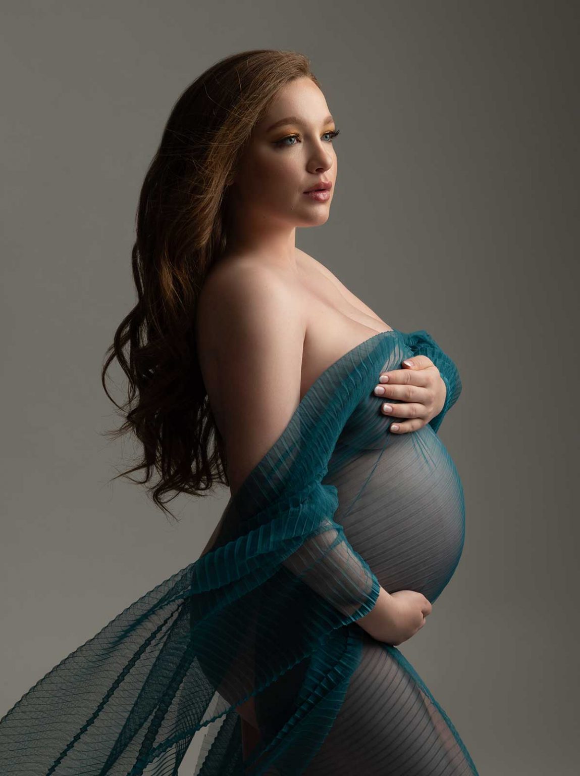 Luxury maternity portrait with red hair and turquoise flying silk