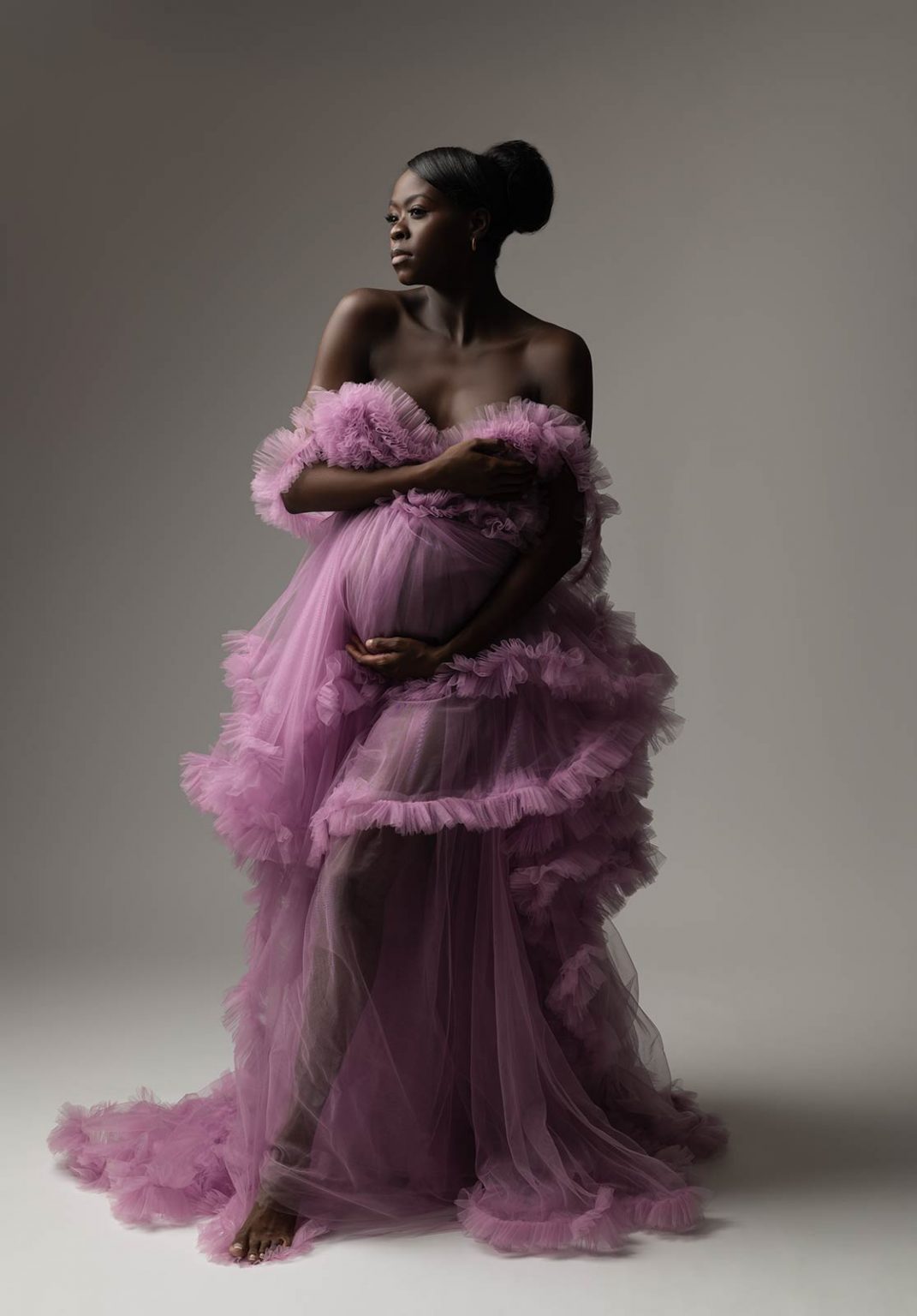 Pregnant woman wearing a purple gown at a maternity photo studio