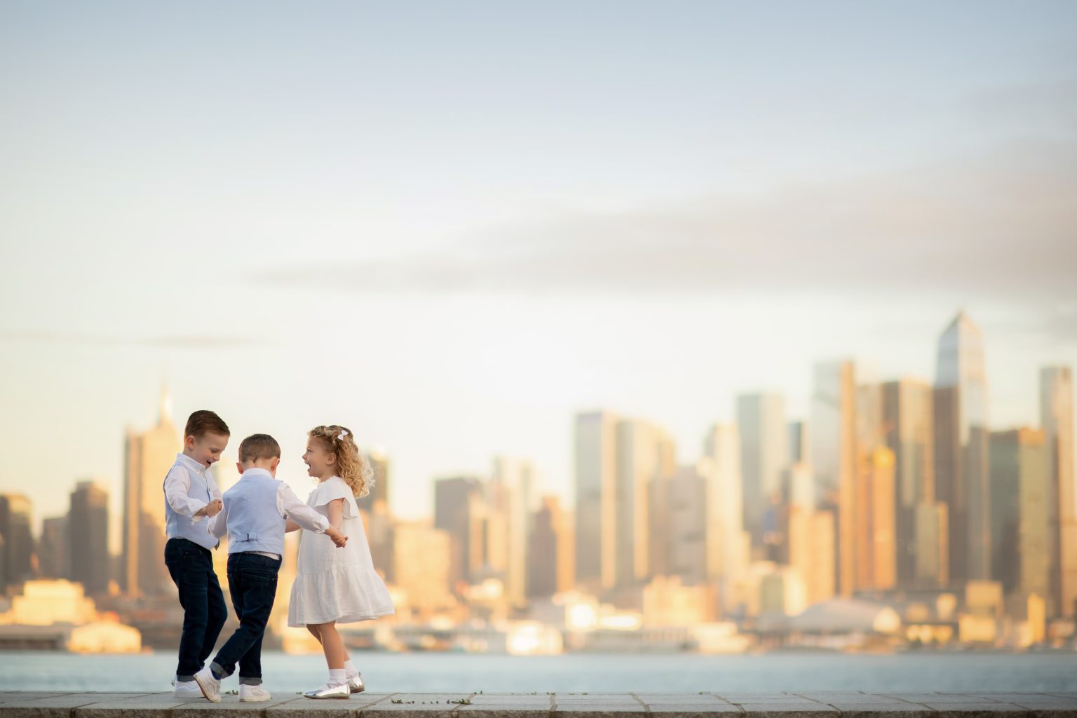 three children playing by the waterfront with skyline views