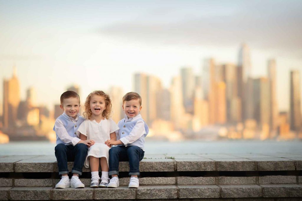 three happy children sitting on the stairs by NYC skyline