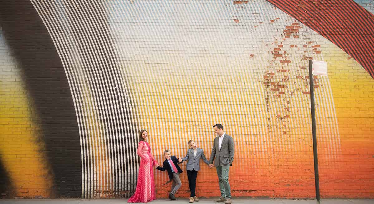 Stylish family sharing a candid moment near a colorful brick wall.