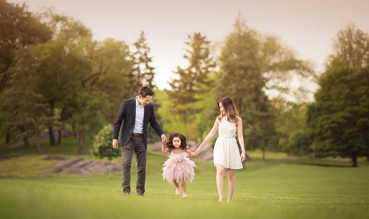 Lifestyle family photo from Central Park with a beautiful family holding their daughter's hands.