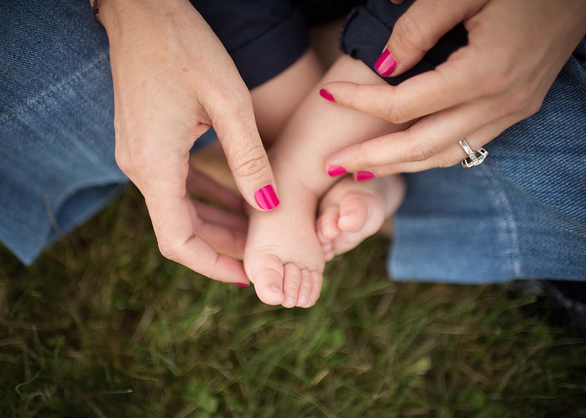 Closeup image of mother's hands holding her son's baby feet.