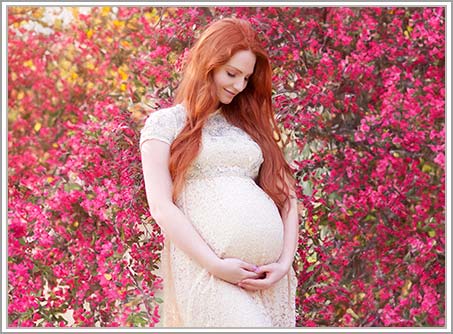 Pregnant woman standing amidst cherry blossoms