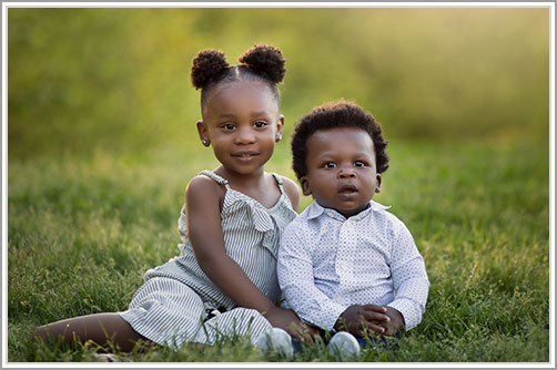 Brother and sister sitting in grass in NYC's iconic Central Park