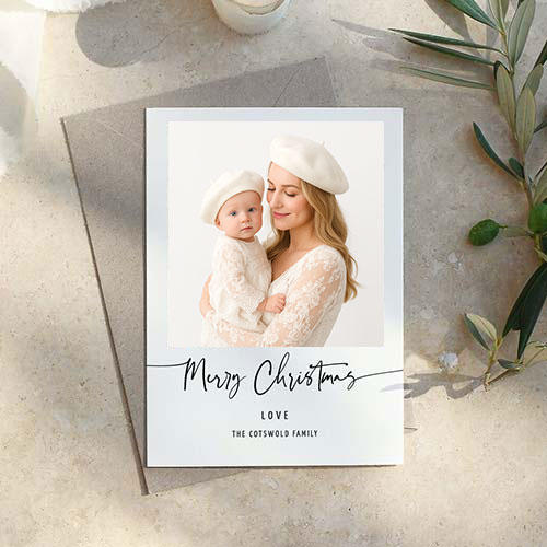 A Christmas card from an NYC Holiday Photoshoot shows a woman and a baby, both in white outfits and berets. The card reads 